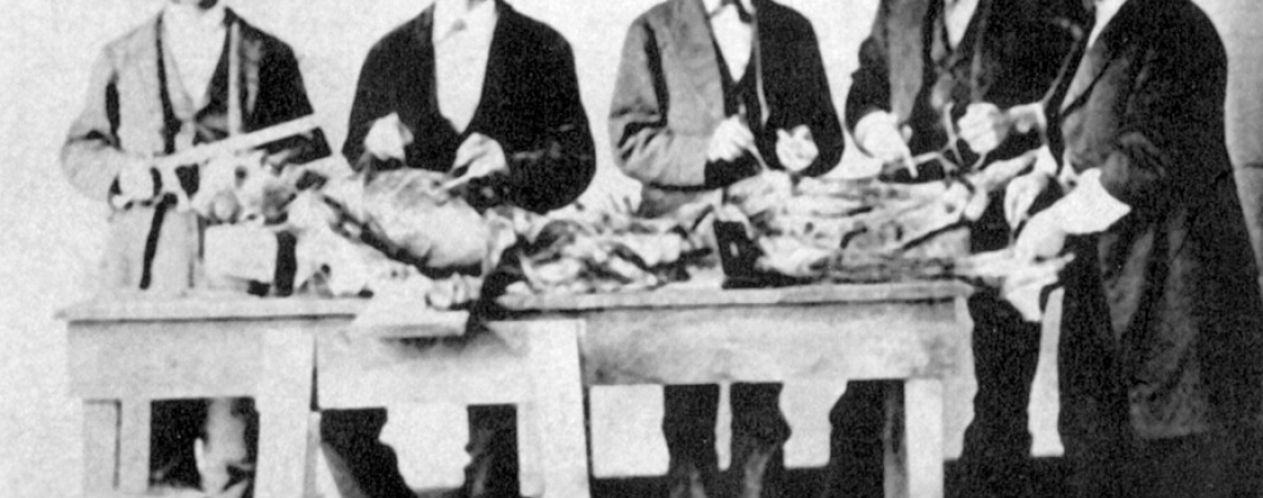 A group of men standing around a surgical table in the 1800s
